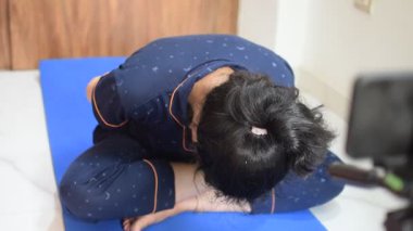 Evde yoga yapan genç Hintli bir kadın çevrimiçi yoga seansında güzel bir kız temel yoga pozisyonunda Asyalı bir kadın kapalı alanda yoga yapıyor. 