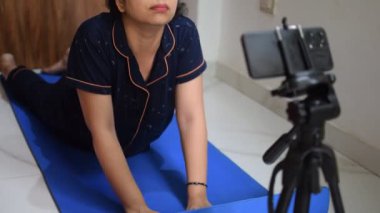 Evde yoga yapan genç Hintli bir kadın çevrimiçi yoga seansında güzel bir kız temel yoga pozisyonunda Asyalı bir kadın kapalı alanda yoga yapıyor. 
