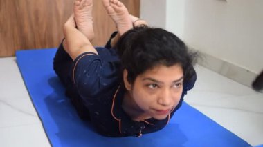 Evde yoga yapan genç Hintli bir kadın çevrimiçi yoga seansında güzel bir kız temel yoga pozisyonunda Asyalı bir kadın kapalı alanda yoga yapıyor. 