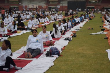 Yeni Delhi, Hindistan, 21 Haziran 2025 - Uluslararası Yoga Günü 'nde Delhi' deki Yamuna Spor Kompleksi 'nde grup Yoga egzersiz oturumu, kriket stadyumunda yoga sınıfına katılan büyük bir grup yetişkin