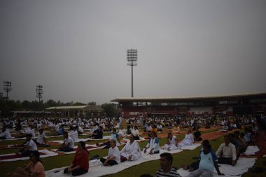 Yeni Delhi, Hindistan, 21 Haziran 2025 - Uluslararası Yoga Günü 'nde Delhi' deki Yamuna Spor Kompleksi 'nde grup Yoga egzersiz oturumu, kriket stadyumunda yoga sınıfına katılan büyük bir grup yetişkin