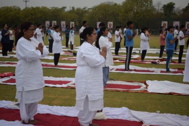 Yeni Delhi, Hindistan, 21 Haziran 2025 - Uluslararası Yoga Günü 'nde Delhi' deki Yamuna Spor Kompleksi 'nde grup Yoga egzersiz oturumu, kriket stadyumunda yoga sınıfına katılan büyük bir grup yetişkin