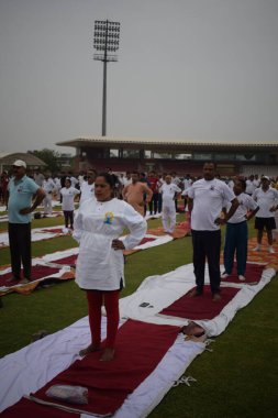 Yeni Delhi, Hindistan, 21 Haziran 2025 - Uluslararası Yoga Günü 'nde Delhi' deki Yamuna Spor Kompleksi 'nde grup Yoga egzersiz oturumu, kriket stadyumunda yoga sınıfına katılan büyük bir grup yetişkin