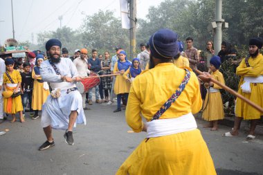 Delhi, Hindistan, 17 Kasım 2024 - Doğu Delhi bölgesinde Guru Nanak Dev, Nagar Kirtan 'ın doğum günü dolayısıyla geleneksel Nagar Kirtan, geleneksel Nagar geçit töreninde Sihler gatka ve dövüş sanatlarını sergiliyor