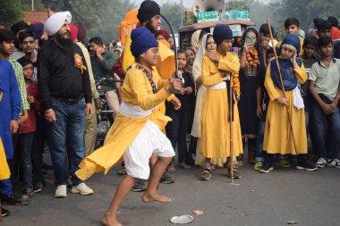 Delhi, Hindistan, 17 Kasım 2024 - Doğu Delhi bölgesinde Guru Nanak Dev, Nagar Kirtan 'ın doğum günü dolayısıyla geleneksel Nagar Kirtan, geleneksel Nagar geçit töreninde Sihler gatka ve dövüş sanatlarını sergiliyor