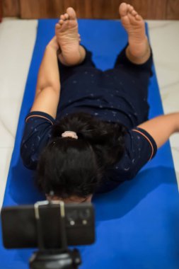 Evde yoga yapan genç Hintli bir kadın çevrimiçi yoga seansında güzel bir kız temel yoga pozisyonunda Asyalı bir kadın kapalı alanda yoga yapıyor.