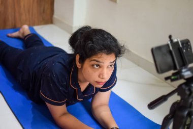 Evde yoga yapan genç Hintli bir kadın çevrimiçi yoga seansında güzel bir kız temel yoga pozisyonunda Asyalı bir kadın kapalı alanda yoga yapıyor.