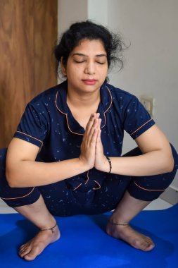 Evde yoga yapan genç Hintli bir kadın çevrimiçi yoga seansında güzel bir kız temel yoga pozisyonunda Asyalı bir kadın kapalı alanda yoga yapıyor.