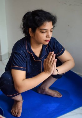 Evde yoga yapan genç Hintli bir kadın çevrimiçi yoga seansında güzel bir kız temel yoga pozisyonunda Asyalı bir kadın kapalı alanda yoga yapıyor.