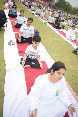 Yeni Delhi, Hindistan, 21 Haziran 2025 - Uluslararası Yoga Günü 'nde Delhi' deki Yamuna Spor Kompleksi 'nde grup Yoga egzersiz oturumu, kriket stadyumunda yoga sınıfına katılan büyük bir grup yetişkin