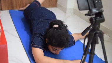 Evde yoga yapan genç Hintli bir kadın çevrimiçi yoga seansında güzel bir kız temel yoga pozisyonunda Asyalı bir kadın kapalı alanda yoga yapıyor. 