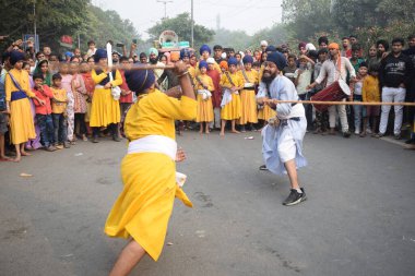 Delhi, Hindistan, 17 Kasım 2024 - Doğu Delhi bölgesinde Guru Nanak Dev, Nagar Kirtan 'ın doğum günü dolayısıyla geleneksel Nagar Kirtan, geleneksel Nagar geçit töreninde Sihler gatka ve dövüş sanatlarını sergiliyor