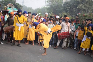 Delhi, Hindistan, 17 Kasım 2024 - Doğu Delhi bölgesinde Guru Nanak Dev, Nagar Kirtan 'ın doğum günü dolayısıyla geleneksel Nagar Kirtan, geleneksel Nagar geçit töreninde Sihler gatka ve dövüş sanatlarını sergiliyor