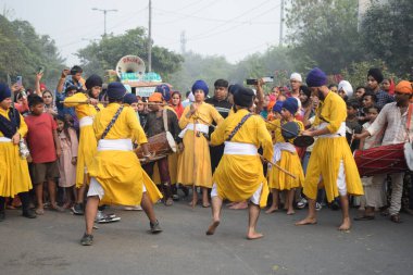 Delhi, Hindistan, 17 Kasım 2024 - Doğu Delhi bölgesinde Guru Nanak Dev, Nagar Kirtan 'ın doğum günü dolayısıyla geleneksel Nagar Kirtan, geleneksel Nagar geçit töreninde Sihler gatka ve dövüş sanatlarını sergiliyor