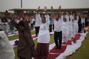 Yeni Delhi, Hindistan, 21 Haziran 2025 - Uluslararası Yoga Günü 'nde Delhi' deki Yamuna Spor Kompleksi 'nde grup Yoga egzersiz oturumu, kriket stadyumunda yoga sınıfına katılan büyük bir grup yetişkin