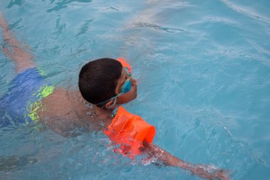 Havuzda yüzen mutlu Hintli çocuk, sıcak yaz tatillerinde hava tüpüyle birlikte yüzen çocuk, büyük bir havuzda yüzen çocuk..