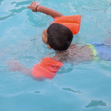 Havuzda yüzen mutlu Hintli çocuk, sıcak yaz tatillerinde hava tüpüyle birlikte yüzen çocuk, büyük bir havuzda yüzen çocuk..