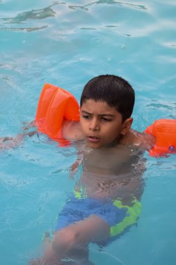 Havuzda yüzen mutlu Hintli çocuk, sıcak yaz tatillerinde hava tüpüyle birlikte yüzen çocuk, büyük bir havuzda yüzen çocuk..