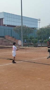 Delhi, Hindistan, 17 Şubat 2025 - Maha Open için kil tenis kortunda antrenörlük yapan genç tenisçiler, yaklaşan turnuva için küçük tenis oyuncuları antrenman yapıyor