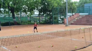 Delhi, Hindistan, 17 Şubat 2025 - Maha Open için kil tenis kortunda antrenörlük yapan genç tenisçiler, yaklaşan turnuva için küçük tenis oyuncuları antrenman yapıyor