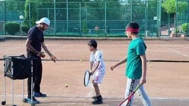 Delhi, Hindistan, 17 Şubat 2025 - Maha Open için kil tenis kortunda antrenörlük yapan genç tenisçiler, yaklaşan turnuva için küçük tenis oyuncuları antrenman yapıyor