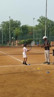 Delhi, Hindistan, 17 Şubat 2025 - Maha Open için kil tenis kortunda antrenörlük yapan genç tenisçiler, yaklaşan turnuva için küçük tenis oyuncuları antrenman yapıyor