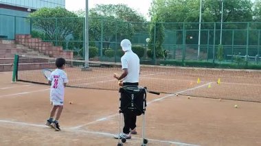 Delhi, Hindistan, 17 Şubat 2025 - Maha Open için kil tenis kortunda antrenörlük yapan genç tenisçiler, yaklaşan turnuva için küçük tenis oyuncuları antrenman yapıyor