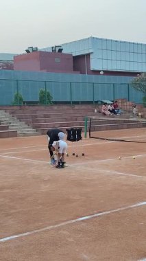 Delhi, Hindistan, 17 Şubat 2025 - Maha Open için kil tenis kortunda antrenörlük yapan genç tenisçiler, yaklaşan turnuva için küçük tenis oyuncuları antrenman yapıyor