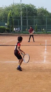 Delhi, Hindistan, 17 Şubat 2025 - Maha Open için kil tenis kortunda antrenörlük yapan genç tenisçiler, yaklaşan turnuva için küçük tenis oyuncuları antrenman yapıyor