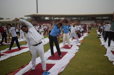 Yeni Delhi, Hindistan, 21 Haziran 2025 - Uluslararası Yoga Günü 'nde Delhi' deki Yamuna Spor Kompleksi 'nde grup Yoga egzersiz oturumu, kriket stadyumunda yoga sınıfına katılan büyük bir grup yetişkin