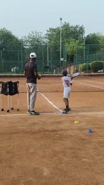 Delhi, Hindistan, 17 Şubat 2025 - Maha Open için kil tenis kortunda antrenörlük yapan genç tenisçiler, yaklaşan turnuva için küçük tenis oyuncuları antrenman yapıyor