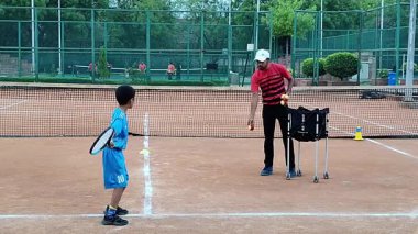 Delhi, Hindistan, 17 Şubat 2025 - Maha Open için kil tenis kortunda antrenörlük yapan genç tenisçiler, yaklaşan turnuva için küçük tenis oyuncuları antrenman yapıyor