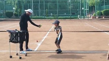 Delhi, Hindistan, 17 Şubat 2025 - Maha Open için kil tenis kortunda antrenörlük yapan genç tenisçiler, yaklaşan turnuva için küçük tenis oyuncuları antrenman yapıyor