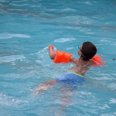 Havuzda yüzen mutlu Hintli çocuk, sıcak yaz tatillerinde hava tüpüyle birlikte yüzen çocuk, büyük bir havuzda yüzen çocuk..