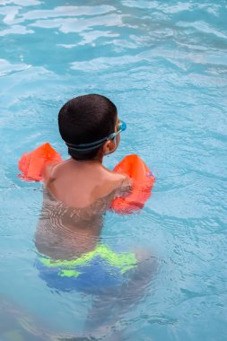 Havuzda yüzen mutlu Hintli çocuk, sıcak yaz tatillerinde hava tüpüyle birlikte yüzen çocuk, büyük bir havuzda yüzen çocuk..