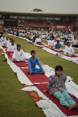 Yeni Delhi, Hindistan, 21 Haziran 2025 - Uluslararası Yoga Günü 'nde Delhi' deki Yamuna Spor Kompleksi 'nde grup Yoga egzersiz oturumu, kriket stadyumunda yoga sınıfına katılan büyük bir grup yetişkin