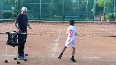 Delhi, Hindistan, 17 Şubat 2025 - Maha Open için kil tenis kortunda antrenörlük yapan genç tenisçiler, yaklaşan turnuva için küçük tenis oyuncuları antrenman yapıyor
