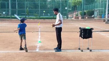 Delhi, Hindistan, 17 Şubat 2025 - Maha Open için kil tenis kortunda antrenörlük yapan genç tenisçiler, yaklaşan turnuva için küçük tenis oyuncuları antrenman yapıyor