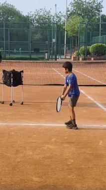 Delhi, Hindistan, 17 Şubat 2025 - Maha Open için kil tenis kortunda antrenörlük yapan genç tenisçiler, yaklaşan turnuva için küçük tenis oyuncuları antrenman yapıyor