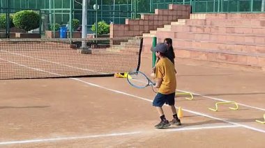 Delhi, Hindistan, 17 Şubat 2025 - Maha Open için kil tenis kortunda antrenörlük yapan genç tenisçiler, yaklaşan turnuva için küçük tenis oyuncuları antrenman yapıyor