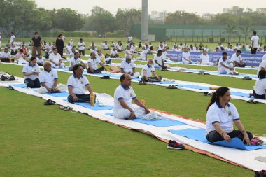Yeni Delhi, Hindistan, 21 Haziran 2025 - Uluslararası Yoga Günü 'nde Delhi' deki Yamuna Spor Kompleksi 'nde grup Yoga egzersiz oturumu, kriket stadyumunda yoga sınıfına katılan büyük bir grup yetişkin