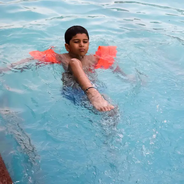 Havuzda yüzen mutlu Hintli çocuk, sıcak yaz tatillerinde hava tüpüyle birlikte yüzen çocuk, büyük bir havuzda yüzen çocuk..