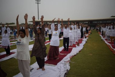 Yeni Delhi, Hindistan, 21 Haziran 2025 - Uluslararası Yoga Günü 'nde Delhi' deki Yamuna Spor Kompleksi 'nde grup Yoga egzersiz oturumu, kriket stadyumunda yoga sınıfına katılan büyük bir grup yetişkin