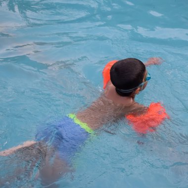 Havuzda yüzen mutlu Hintli çocuk, sıcak yaz tatillerinde hava tüpüyle birlikte yüzen çocuk, büyük bir havuzda yüzen çocuk..