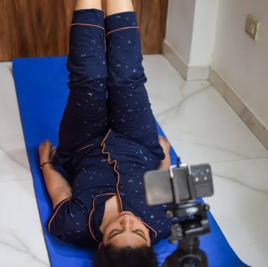Evde yoga yapan genç Hintli bir kadın çevrimiçi yoga seansında güzel bir kız temel yoga pozisyonunda Asyalı bir kadın kapalı alanda yoga yapıyor.