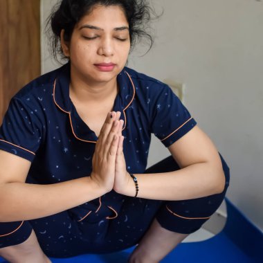 Evde yoga yapan genç Hintli bir kadın çevrimiçi yoga seansında güzel bir kız temel yoga pozisyonunda Asyalı bir kadın kapalı alanda yoga yapıyor.