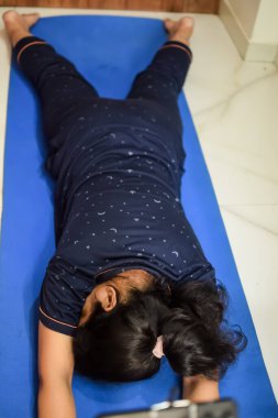 Evde yoga yapan genç Hintli bir kadın çevrimiçi yoga seansında güzel bir kız temel yoga pozisyonunda Asyalı bir kadın kapalı alanda yoga yapıyor.