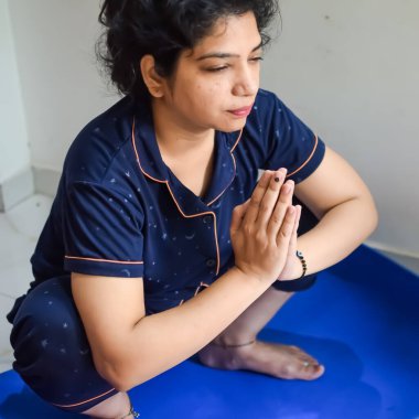 Evde yoga yapan genç Hintli bir kadın çevrimiçi yoga seansında güzel bir kız temel yoga pozisyonunda Asyalı bir kadın kapalı alanda yoga yapıyor.