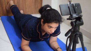 Evde yoga yapan genç Hintli bir kadın çevrimiçi yoga seansında güzel bir kız temel yoga pozisyonunda Asyalı bir kadın kapalı alanda yoga yapıyor. 