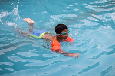 Havuzda yüzen mutlu Hintli çocuk, sıcak yaz tatillerinde hava tüpüyle birlikte yüzen çocuk, büyük bir havuzda yüzen çocuk..